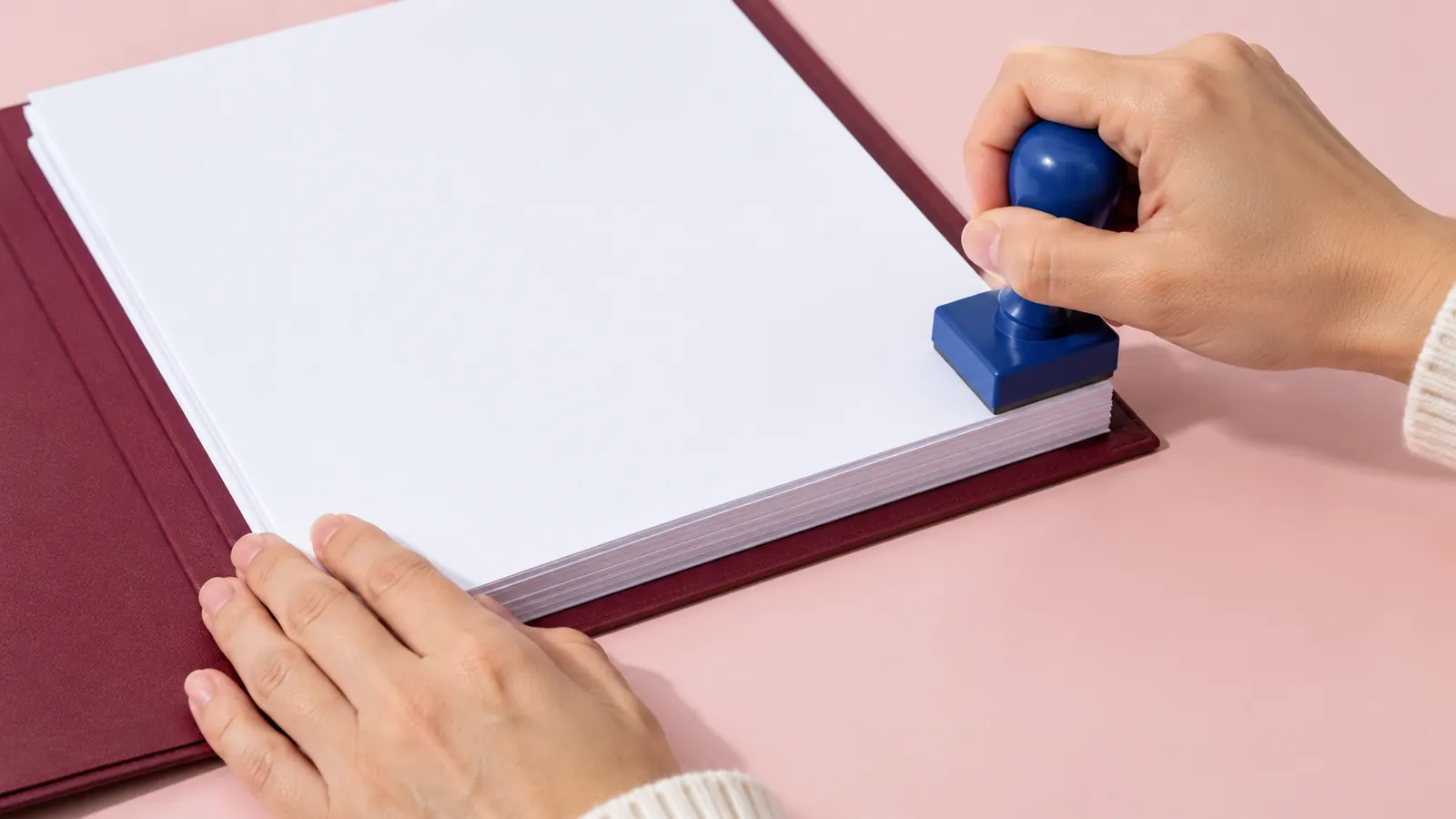 Hand setzt einen blauen Stempel auf einen Dokumentenstapel